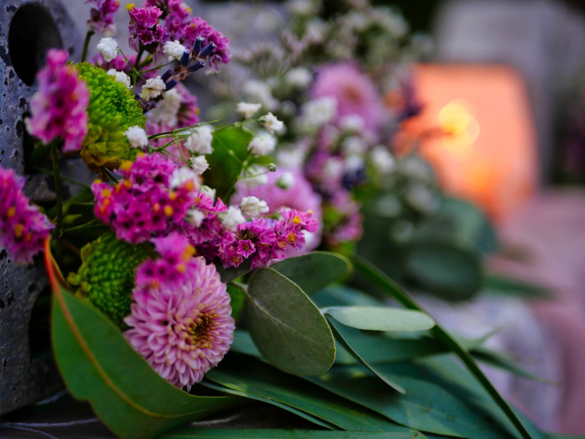 Blumen im Vordergrund, warmes Kerzenlicht im Hintergrund